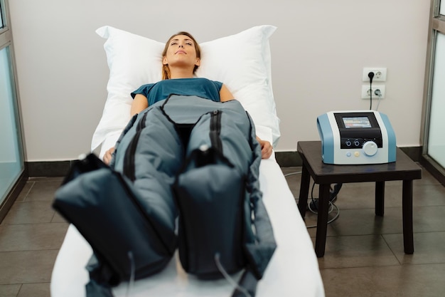 Young woman relaxing with eyes closed during pressotherapy at health spa