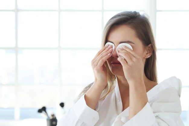Young woman removing facial makeup with make-up remover wipes.