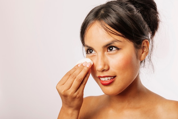 Free photo young woman removing her make up with a cotton pad