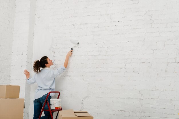 Young woman repainting wall