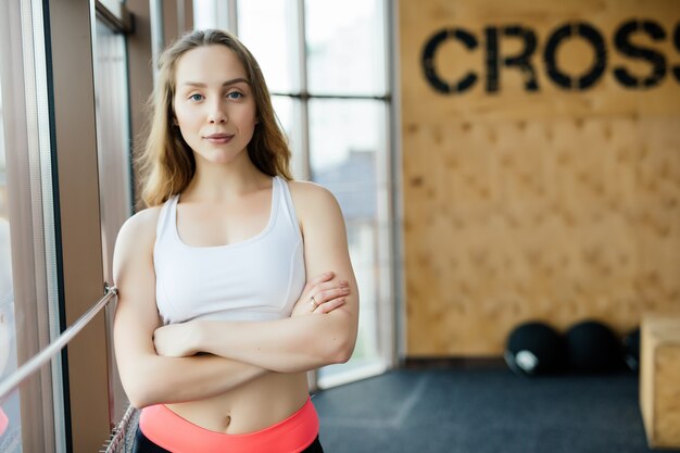 Young woman resting after workout at gym. Fitness female taking break after training session in health club.