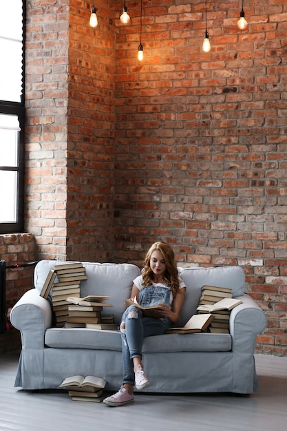 Free photo young woman resting on the couch with a lot of books