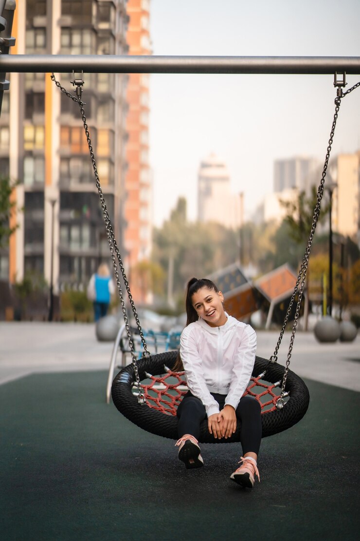 Free Photo young woman rides on a swing. girl resting on the playground.
