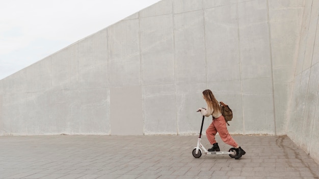 Foto gratuita giovane donna in sella a uno scooter elettrico