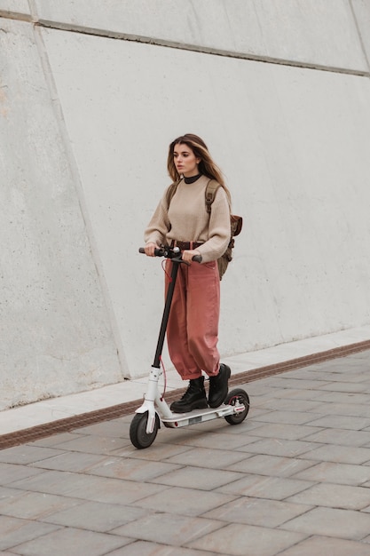 Foto gratuita giovane donna in sella a uno scooter elettrico