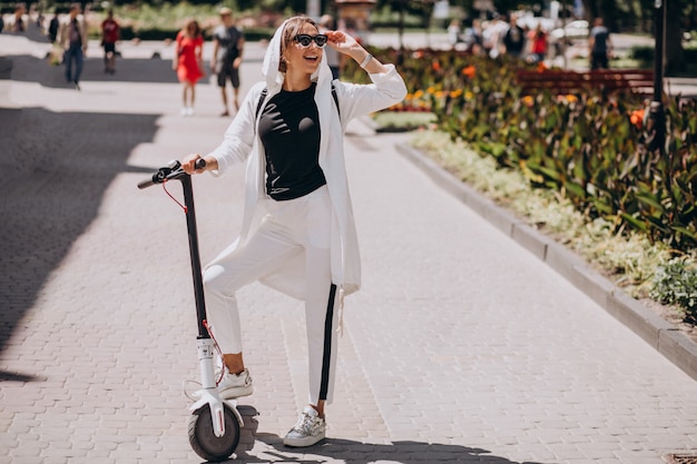 Free photo young woman riding scooter in the street