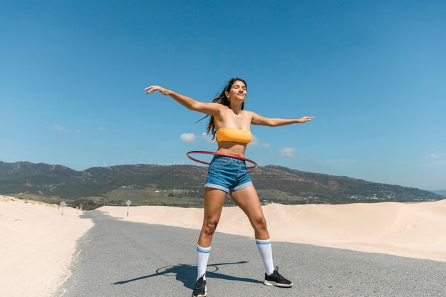 フラフープで遊んで道路上の若い女性