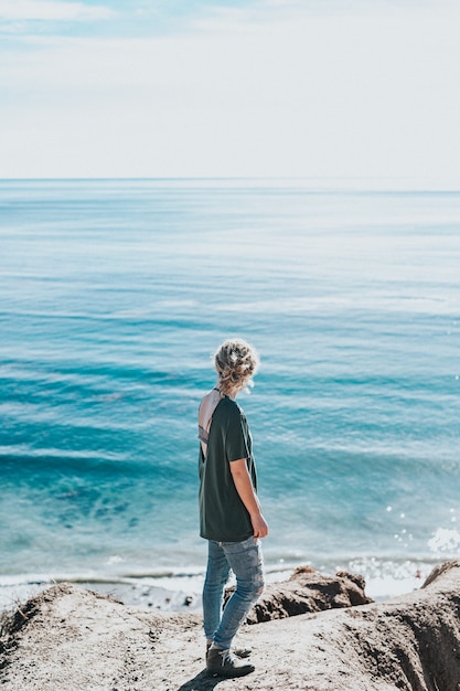 Free photo young woman on a rock near the shore