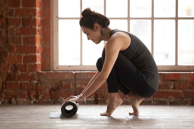 Young woman rolling exercise mat