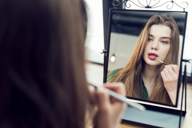 Young woman rouging lips