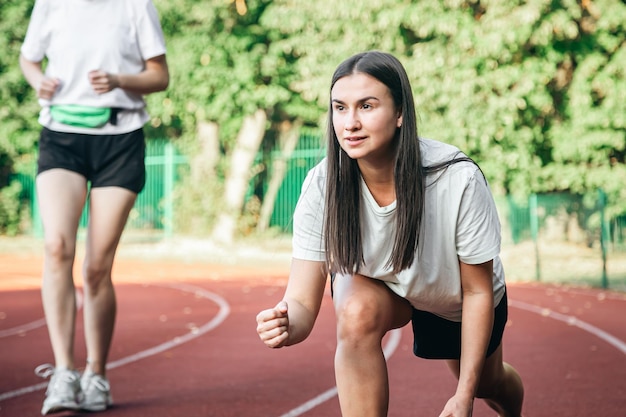 Free photo a young woman runner in start position on running track while work out