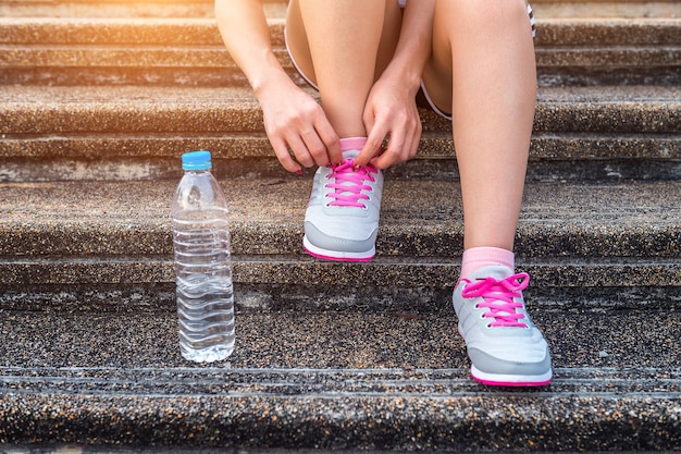 靴ひもを結ぶ若い女性ランナー。運動の概念。