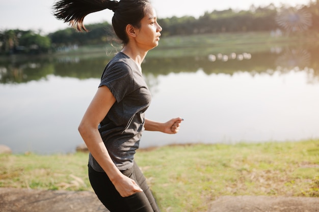 湖の隣に実行している若い女性