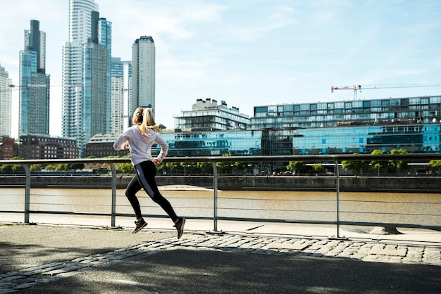 Foto gratuita giovane donna che corre all'aperto con abiti sportivi