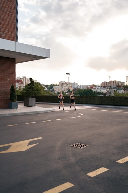 Young woman running on sidewalk in morning. Health conscious concept.