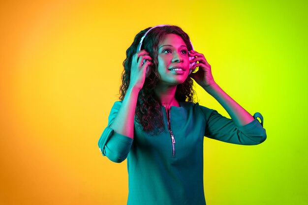 Young woman's portrait isolated on gradient wall in neon light