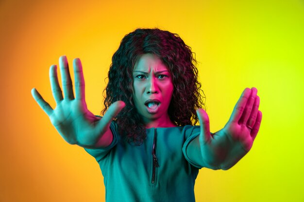 Young woman's portrait isolated on gradient wall in neon light