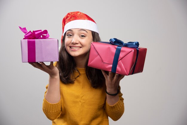 Young woman in Santa Claus red hat with Christmas presents . 