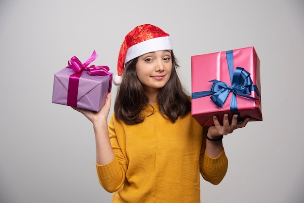 Young woman in Santa hat carrying Christmas presents . 