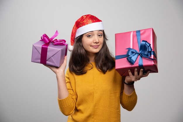 Young woman in Santa hat carrying Christmas presents . 