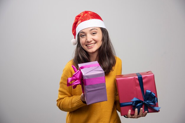 Young woman in Santa hat holding gift boxes. 