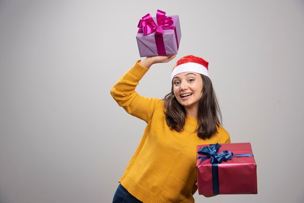 Young woman in Santa hat holding gift boxes. 