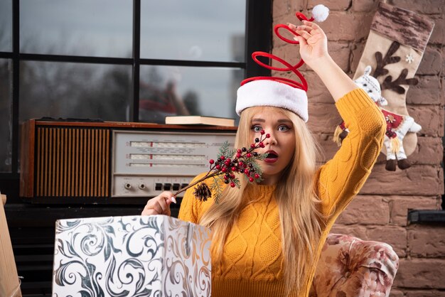 Young woman in Santa hat looking surprised.