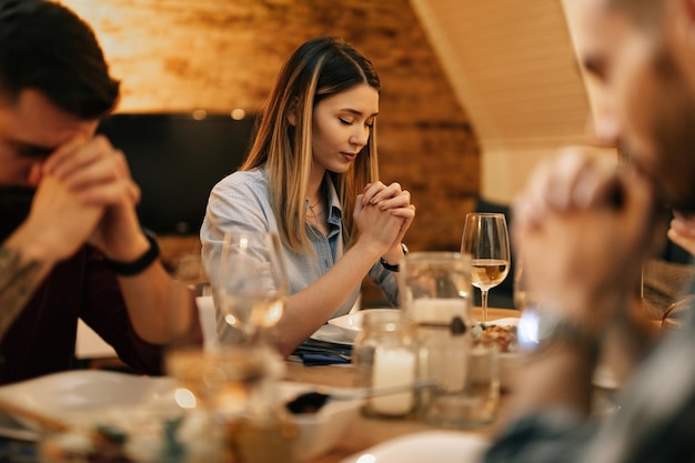 ダイニングルームで友人と夕食をとりながら恵みを言う若い女性