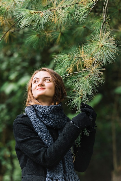 Young woman in scarf holding coniferous twig 