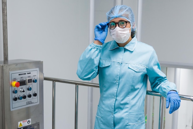 Young woman scientist with glasses near control panel