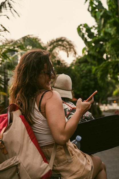 Free photo a young woman on a scooter travels takes pictures on the phone.