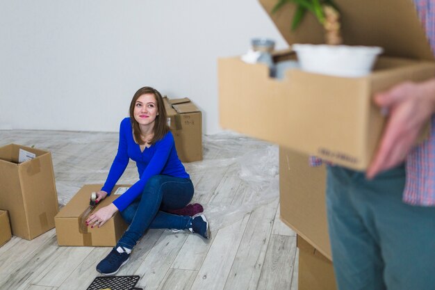 Молодая женщина уплотнения коробки на этаже