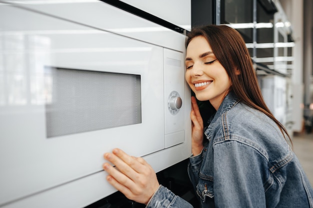 Foto gratuita una giovane donna ha scelto un nuovo forno a microonde in un ipermercato