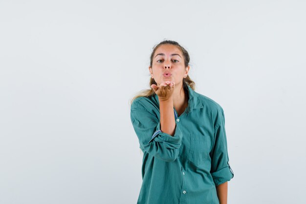 Young woman sending kisses to front in green blouse and looking happy