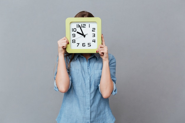 Young Woman in shirt hiding behind the clock