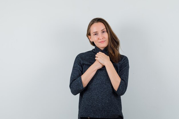 Foto gratuita giovane donna in camicia tenendo le mani sul petto e guardando fiducioso