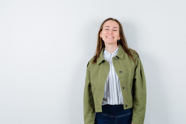 Young woman in shirt, jacket looking at camera while laughing and looking elegant , front view.