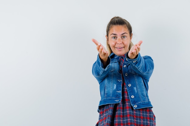 Young woman in shirt, jacket opening arms for hug and looking happy , front view.