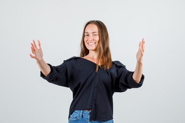 Young woman in shirt, shorts outstretching hands and looking cheery