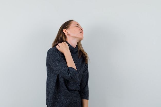 Foto gratuita giovane donna in camicia che soffre di dolore al collo e sembra affaticata