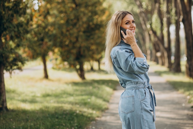 Giovane donna che fa shopping online nel parco