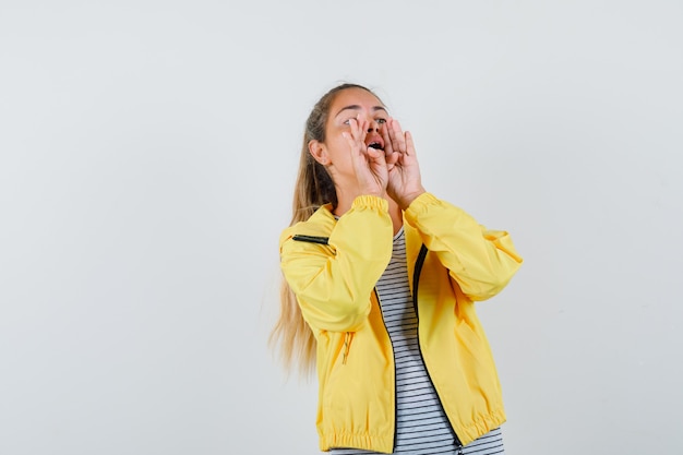 Young woman shouting or announcing something in t-shirt, jacket front view.