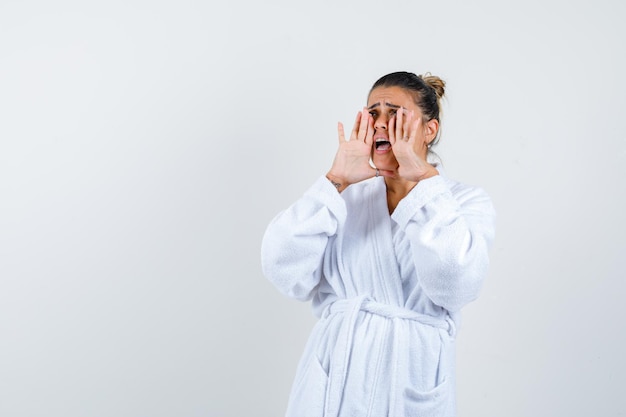 Young woman shouting something in bathrobe and looking worried