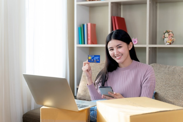 Молодая женщина показать кредитную карту в руке для покупок в Интернете
