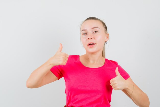 Young woman showing double thumbs up in t-shirt and looking jolly