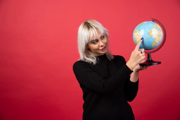 Young woman showing a globe on a red background. High quality photo