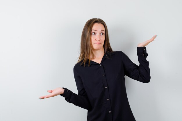 Young woman showing helpless gesture and looking puzzled