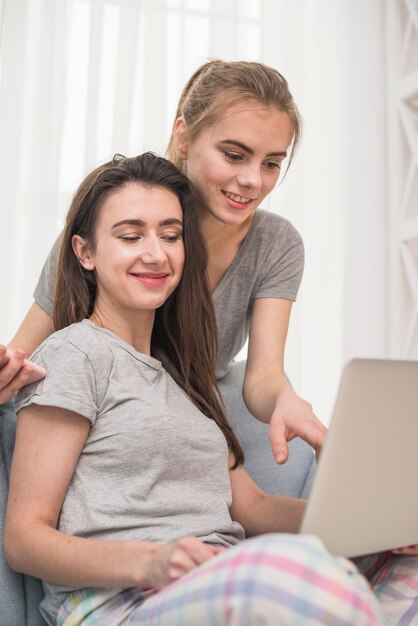 Молодая женщина, показывая ее подруга что-то на ноутбуке