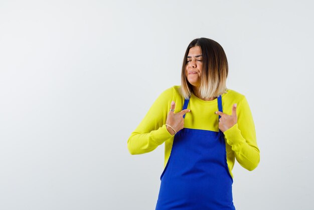 Young woman showing herself with fingers on white background