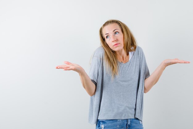 Young woman showing I don't have any idea gesture with hands on white background